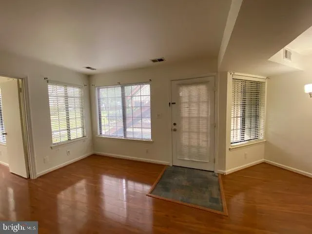 an empty room with wooden floor and windows