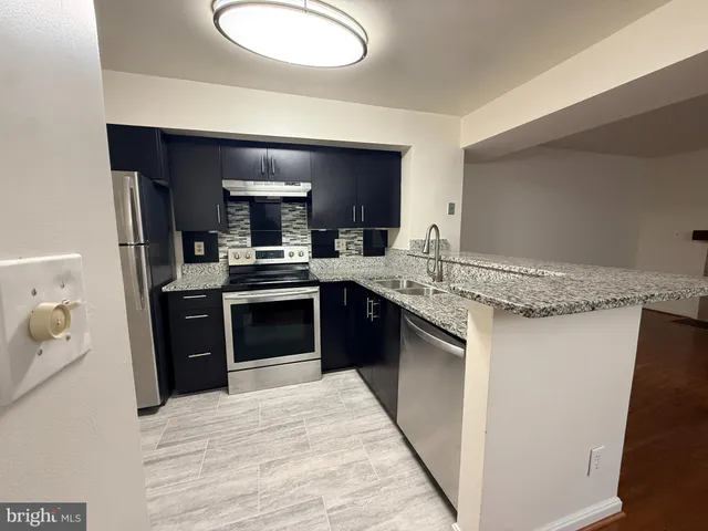 a kitchen with stainless steel appliances granite countertop a stove a sink and a refrigerator