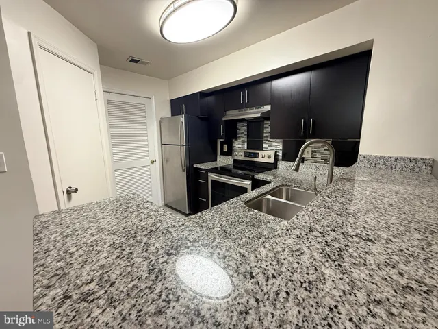 a kitchen with granite countertop a stove and a refrigerator