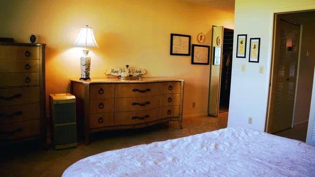 a bedroom with a bed and a lamp on dresser