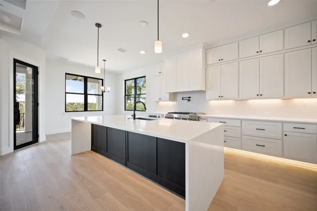 a large kitchen with kitchen island a stove a sink a refrigerator and a fireplace