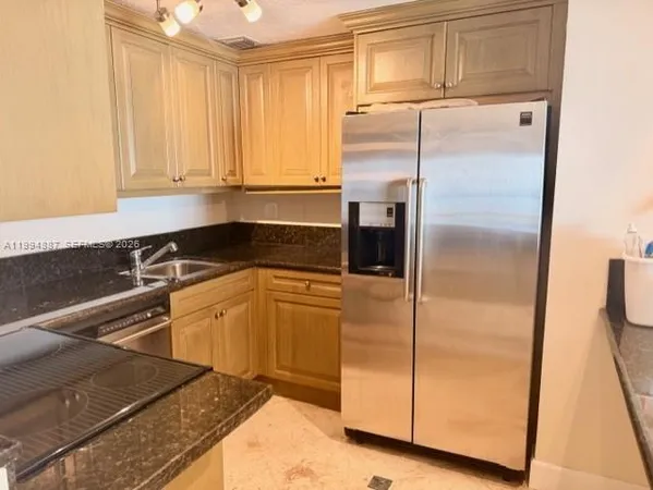 a kitchen with granite countertop a refrigerator and a sink