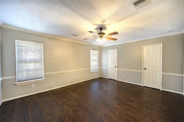 a view of an empty room with a window and wooden floor