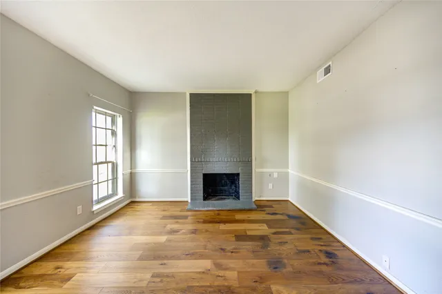 a view of empty room with wooden floor and fireplace