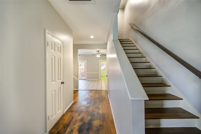 a view of a hallway with wooden floor and stairs