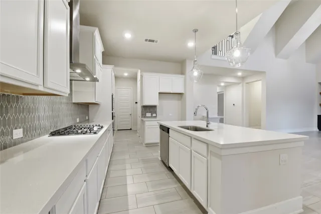 a large white kitchen with stainless steel appliances granite countertop a stove and a sink