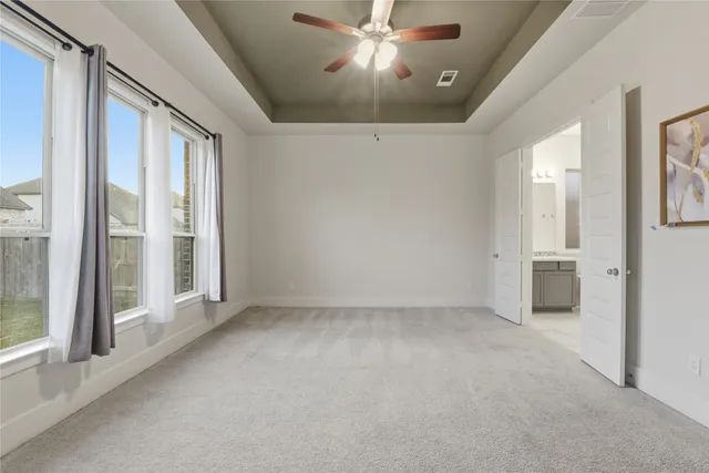 an empty room with a chandelier fan and windows