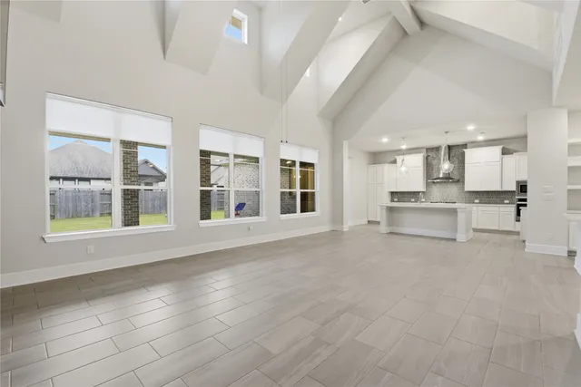 a view of an empty room with kitchen and window