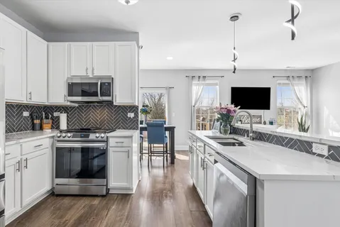 a kitchen with stainless steel appliances granite countertop a stove top oven a sink dishwasher and a refrigerator with wooden floor