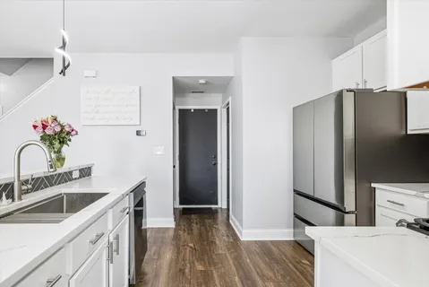 a kitchen with stainless steel appliances a sink dishwasher a refrigerator and a stove with wooden floor