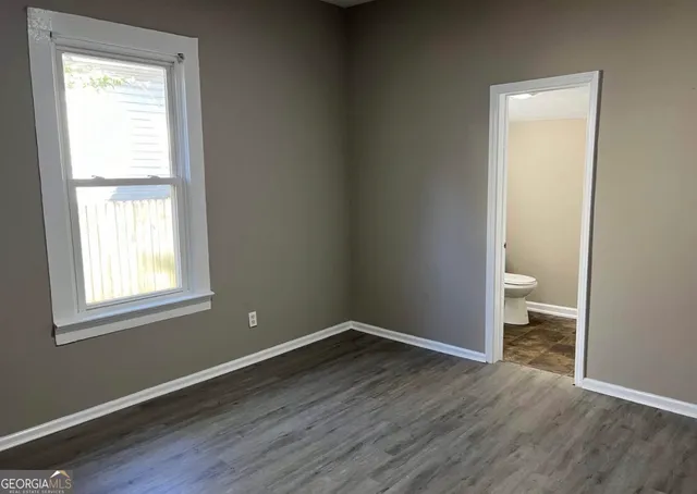 a view of an empty room with a window and wooden floor