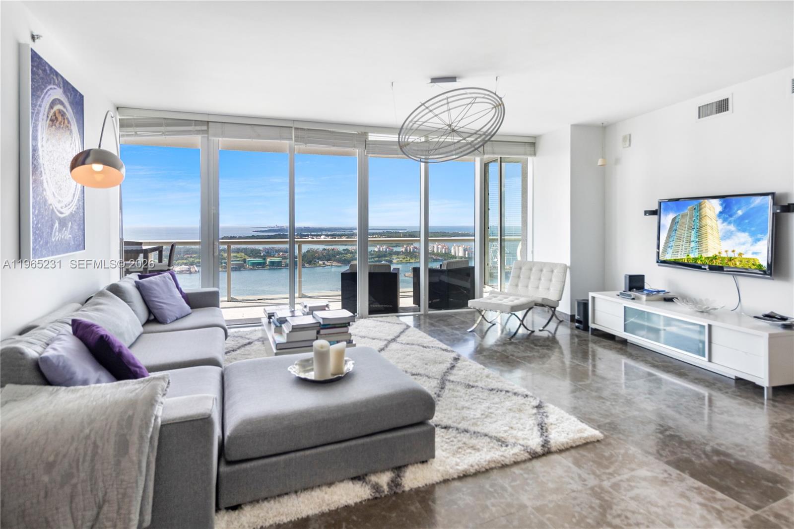 450 Alton Road, Unit 3703 Miami Beach, FL 33139 - Photo 1 of 27 a living room with furniture large window and flat screen tv