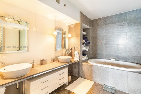 a bathroom with a double vanity sink a mirror a bathtub and toilet