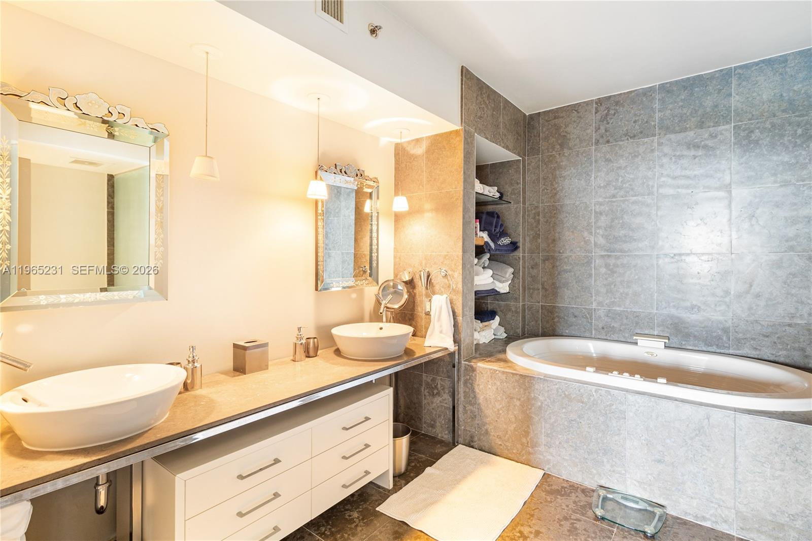 450 Alton Road, Unit 3703 Miami Beach, FL 33139 - Photo 13 of 27 a bathroom with a double vanity sink a mirror a bathtub and toilet