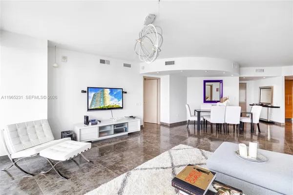 a living room with furniture a dining table and a chandelier