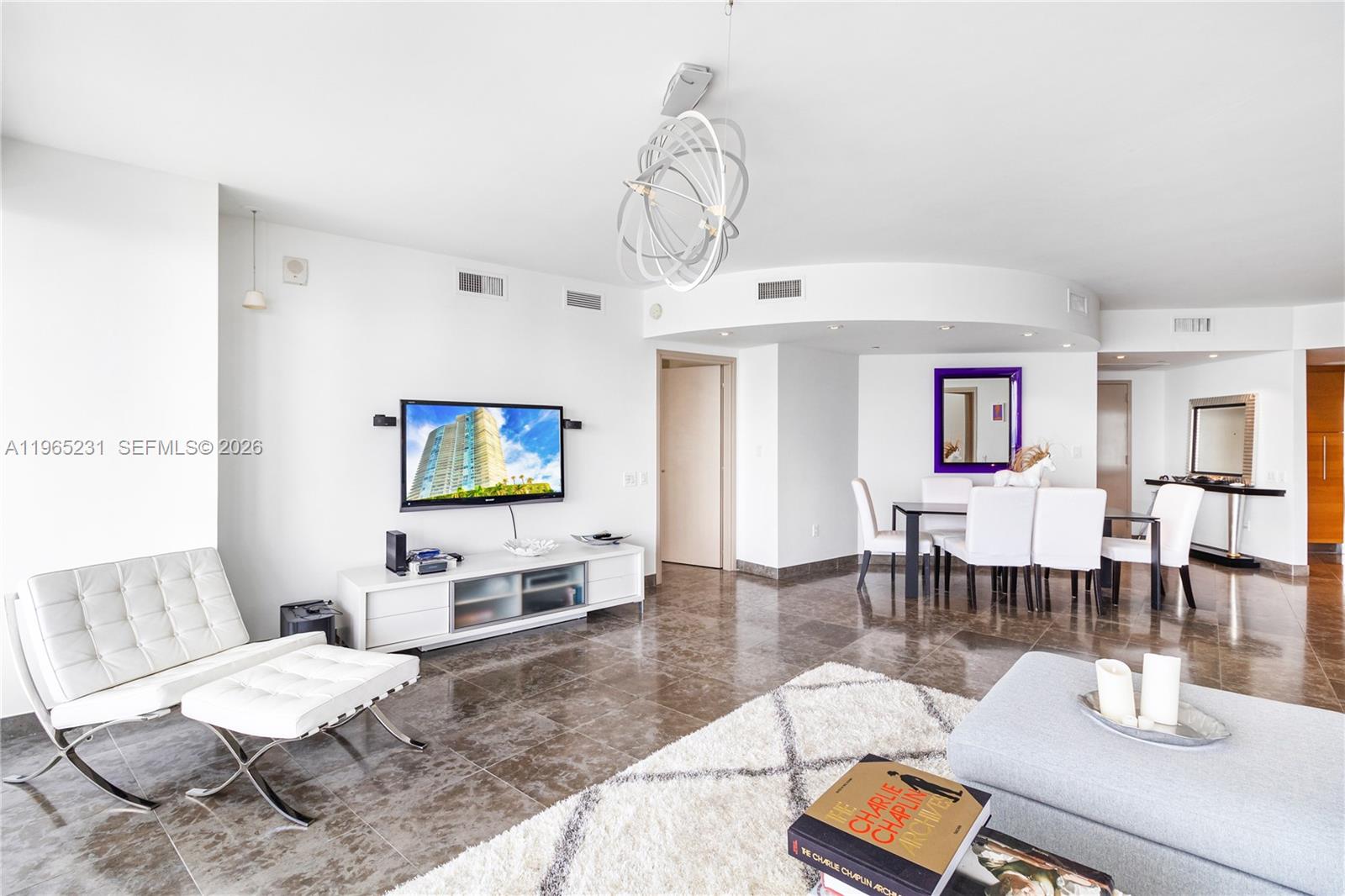 450 Alton Road, Unit 3703 Miami Beach, FL 33139 - Photo 4 of 27 a living room with furniture a dining table and a chandelier