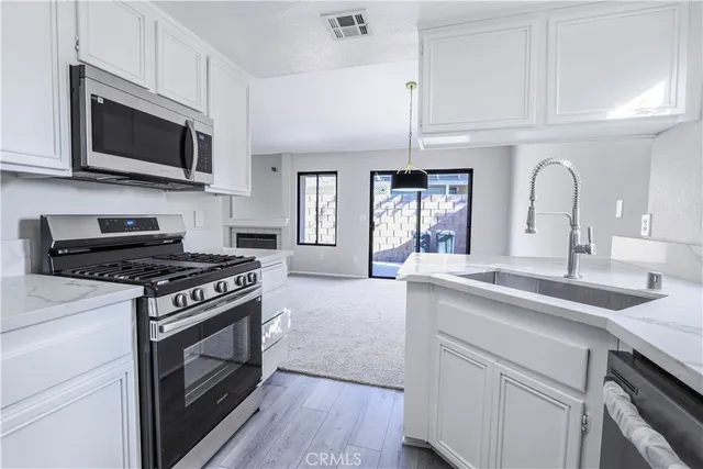 a kitchen with stainless steel appliances a sink dishwasher stove and microwave with wooden floor
