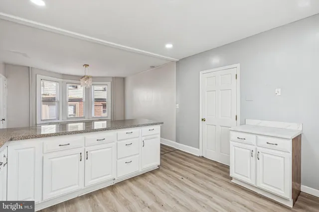 a kitchen with granite countertop white cabinets stainless steel appliances and a window