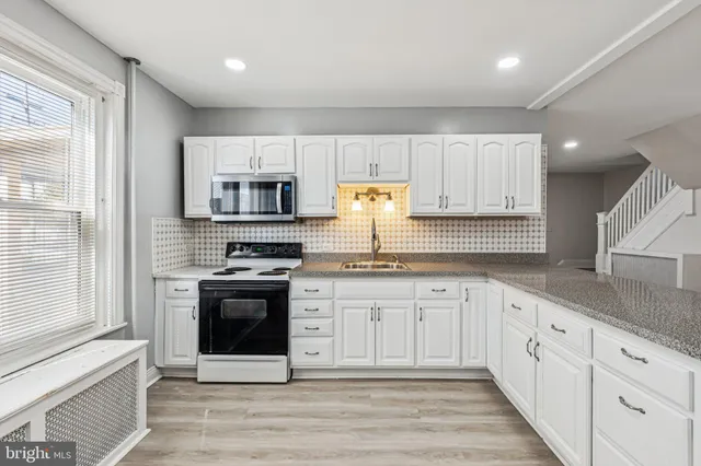 a kitchen with granite countertop white cabinets and white appliances