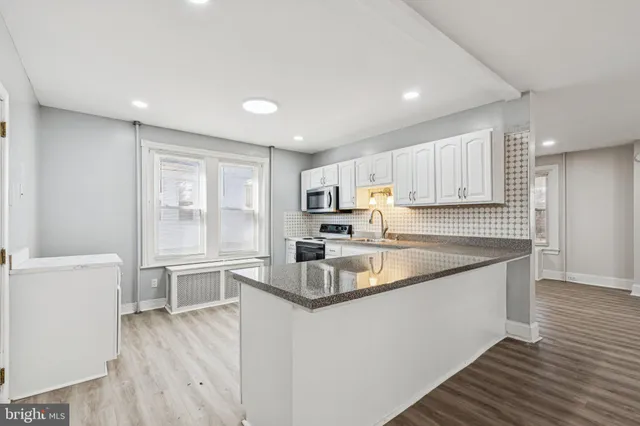 a large kitchen with stainless steel appliances granite countertop a large counter top and a refrigerator