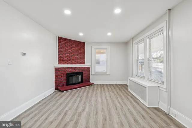 an empty room with wooden floor fireplace and windows