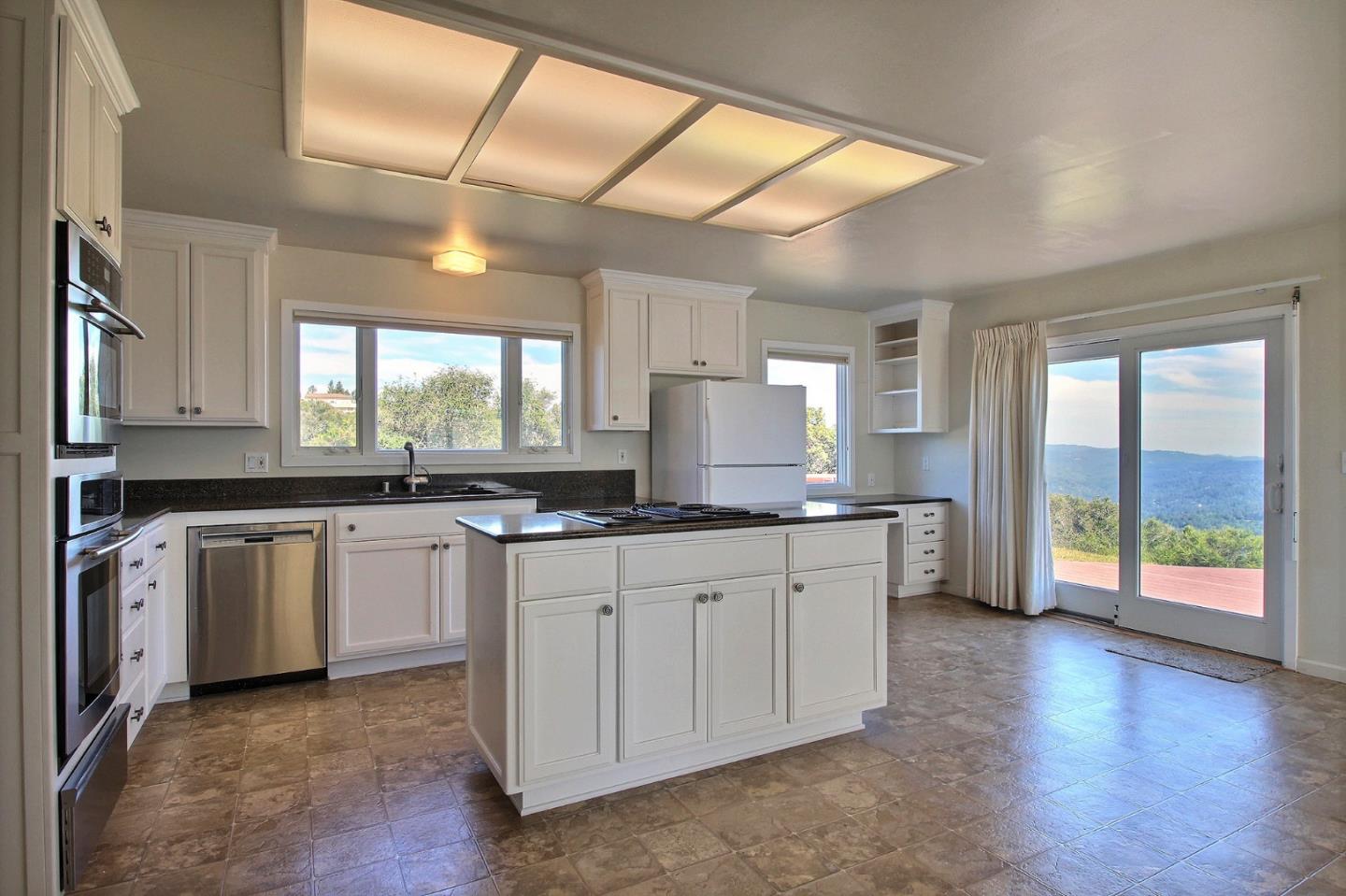 16999 McGill Road Saratoga, CA 95070 - Photo 17 of 41 a large kitchen with granite countertop a large window and white cabinets