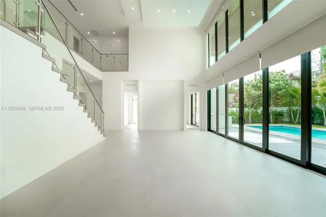 an empty room with chandelier fan and windows