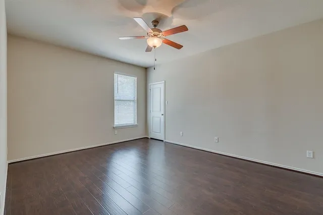 an empty room with wooden floor and ceiling fan