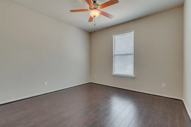 an empty room with wooden floor chandelier fan and windows