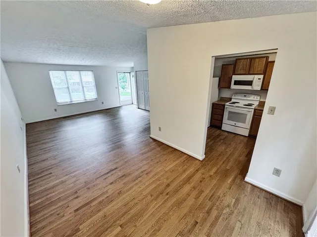 an empty room with wooden floor fireplace and windows