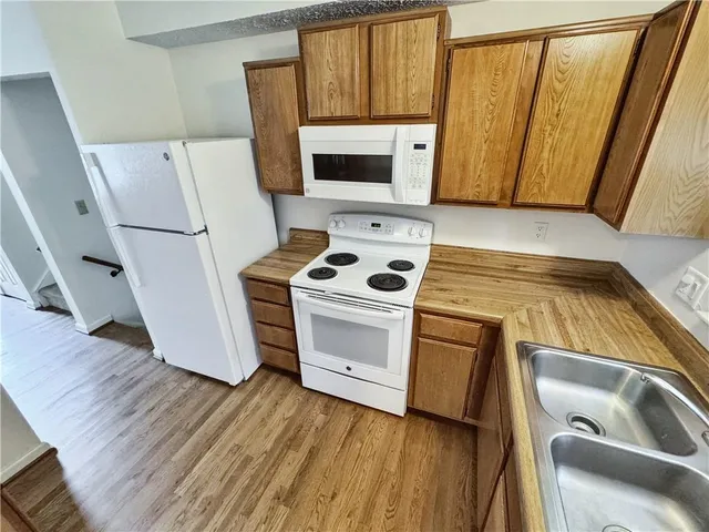 a kitchen with a white stove top oven and a sink with wooden floor