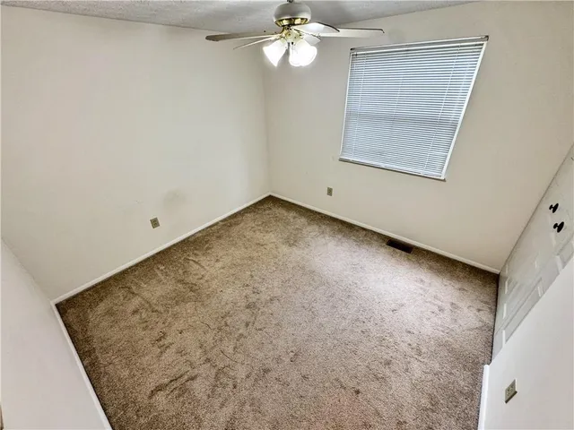 an empty room with a chandelier fan and windows