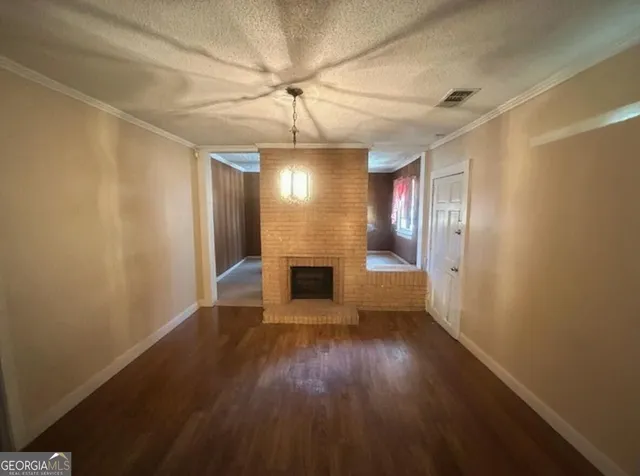 an empty room with wooden floor fireplace and windows