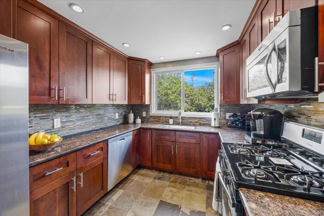 a kitchen with stainless steel appliances granite countertop wooden cabinets stove top oven and sink