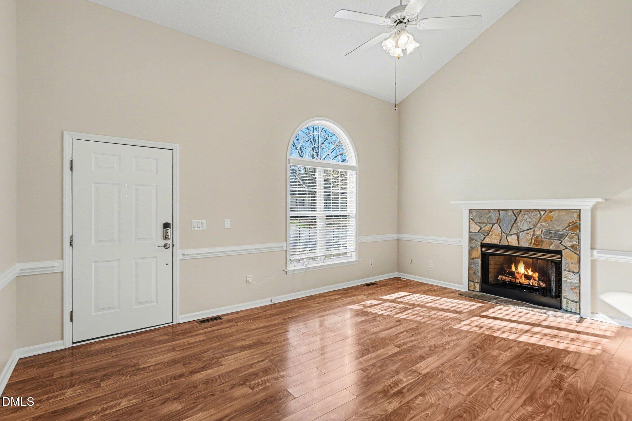 284 Dullis Circle Garner, NC 27529 - Photo 5 of 35 an empty room with windows a fireplace and wooden floor