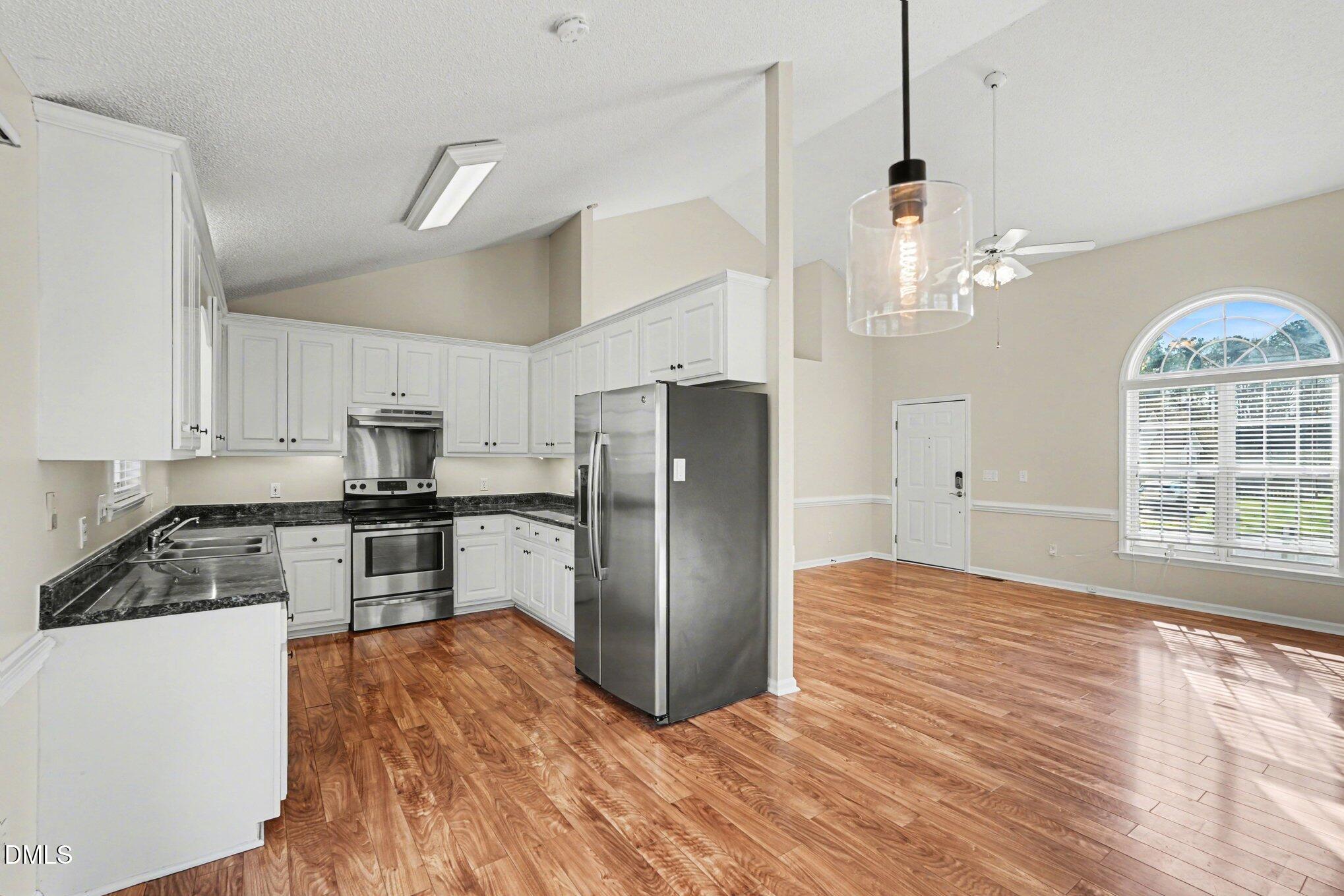 284 Dullis Circle Garner, NC 27529 - Photo 9 of 35 a kitchen with granite countertop stainless steel appliances a refrigerator cabinets and wooden floor
