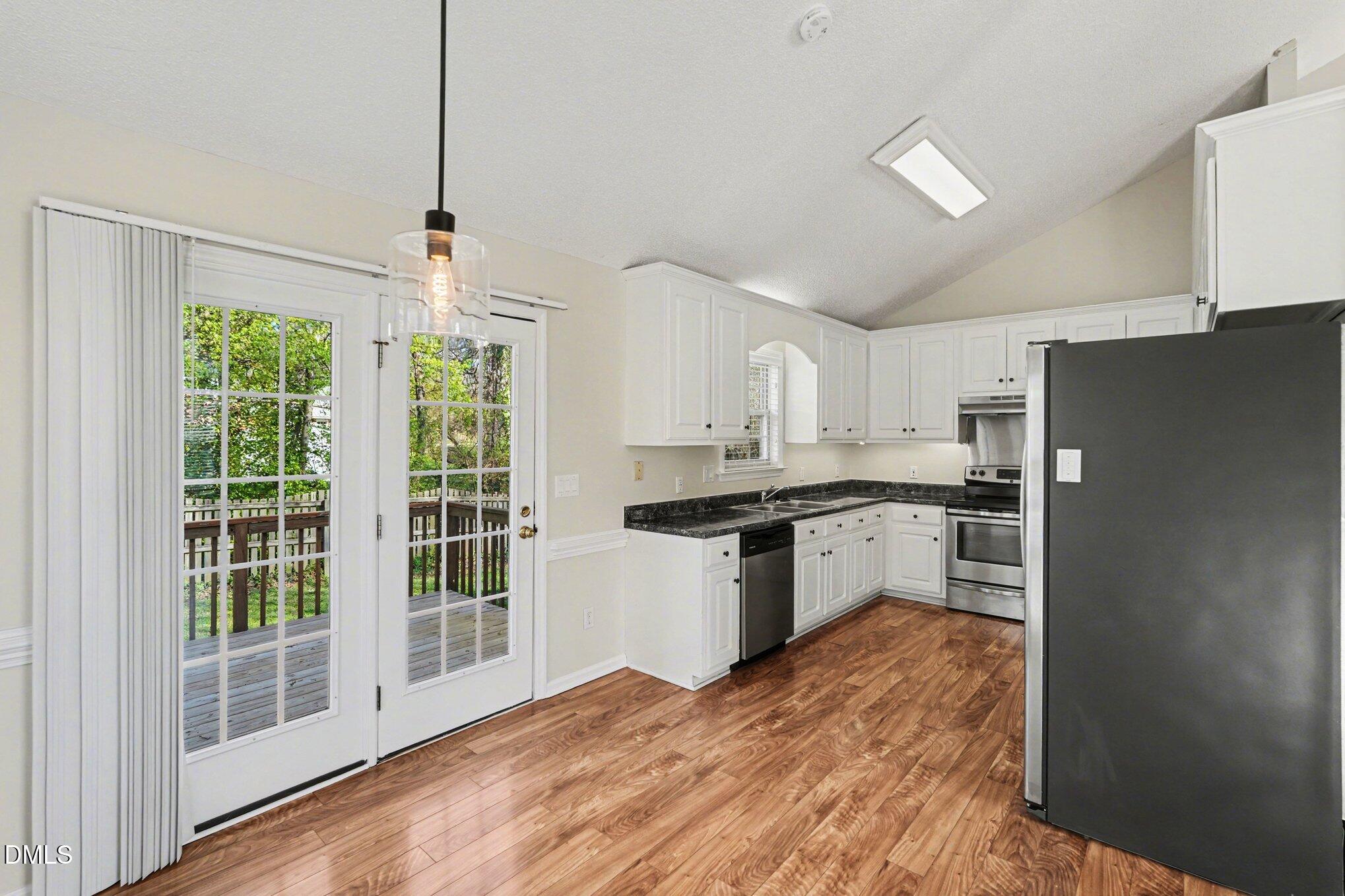 284 Dullis Circle Garner, NC 27529 - Photo 10 of 35 a kitchen with granite countertop a refrigerator a sink a stove and white cabinets
