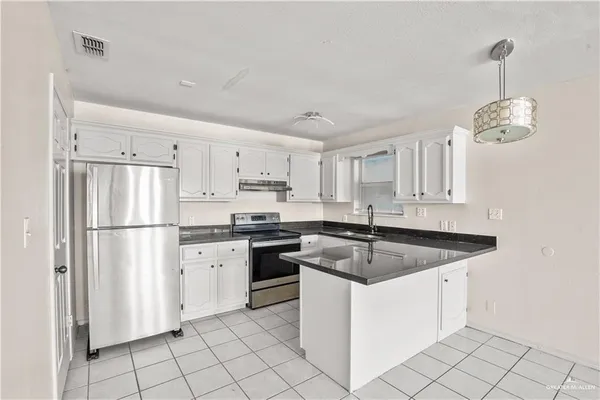 a kitchen with granite countertop white cabinets white stainless steel appliances and a sink