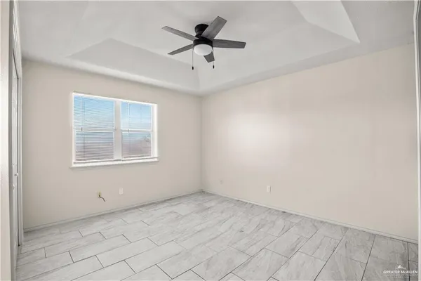 an empty room with chandelier fan and windows
