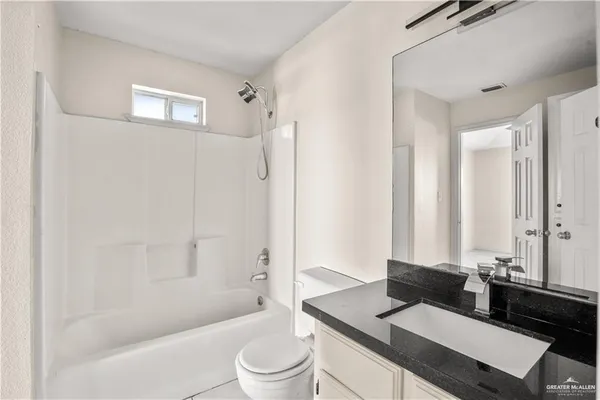 a bathroom with a granite countertop sink toilet a mirror and shower