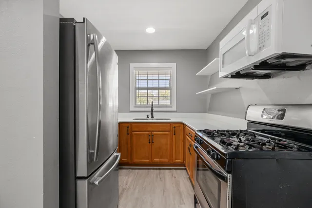 a kitchen with stainless steel appliances a refrigerator a sink and wooden cabinets
