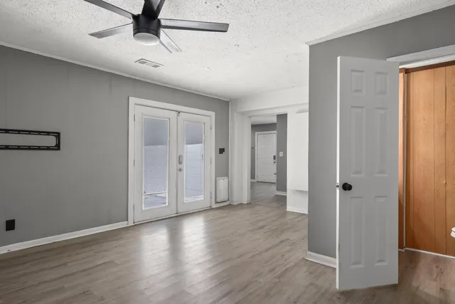 an empty room with wooden floor closet and windows