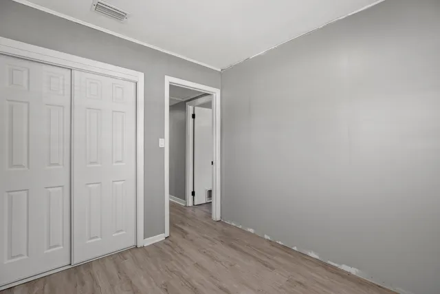 a view of an empty room with closet and wooden floor