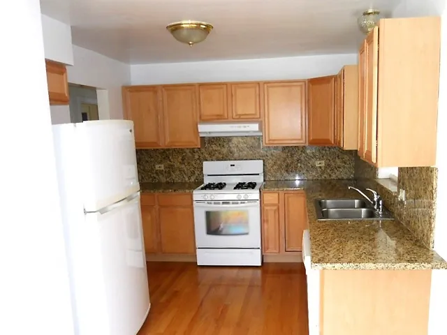 a kitchen with a refrigerator a stove a sink dishwasher and wooden cabinets