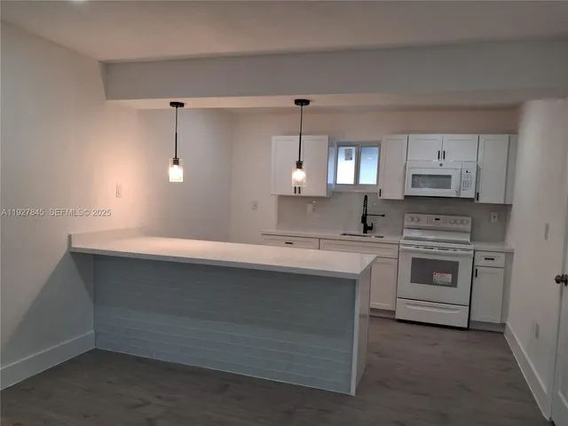 a kitchen with white cabinets and white appliances