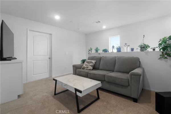 a living room with furniture a flat screen tv and a window