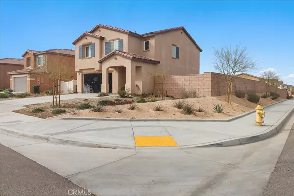 a view of a white house with a large pool and lawn chairs under an umbrella