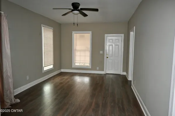 a view of an empty room with wooden floor and window