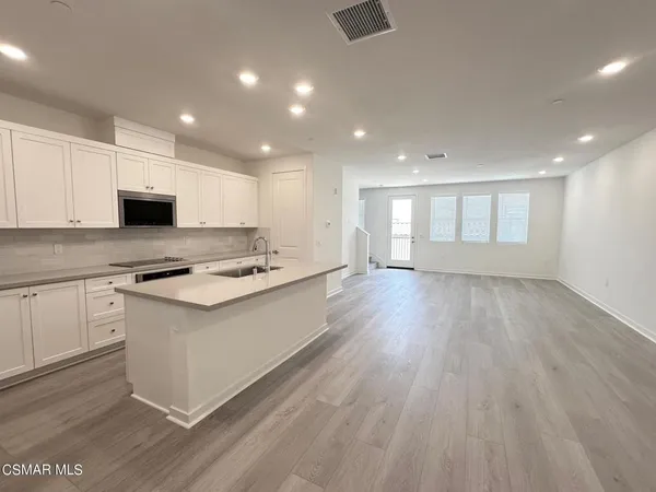 a large kitchen with stainless steel appliances granite countertop a lot of counter space and wooden floor