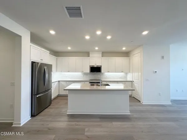 a view of kitchen with stainless steel appliances granite countertop refrigerator and stove top oven
